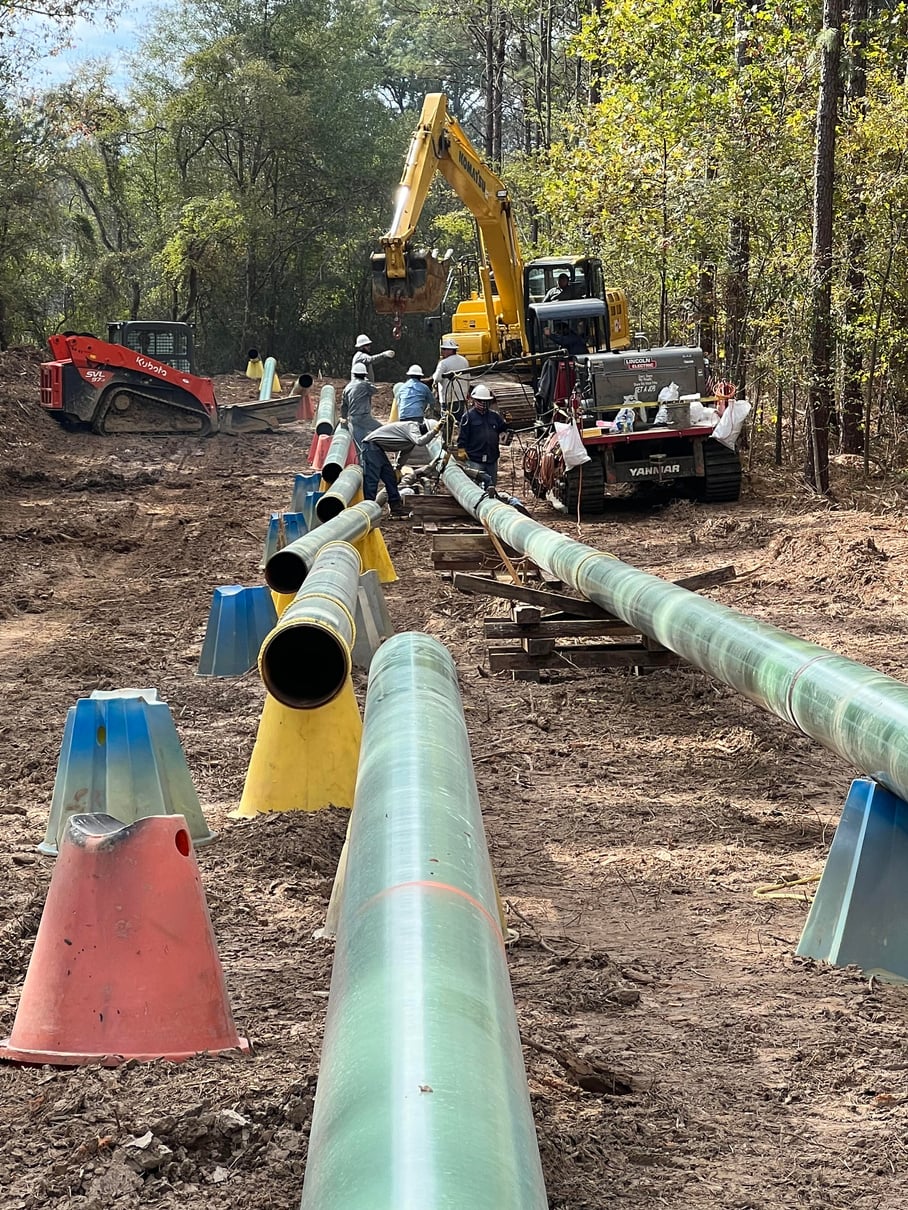 Pipeline crew and excavator in a wooded right-of-way